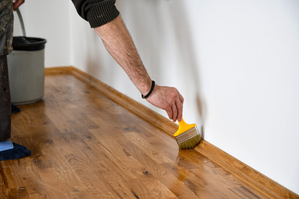 Professional applying low voc floor finish to a baseboard