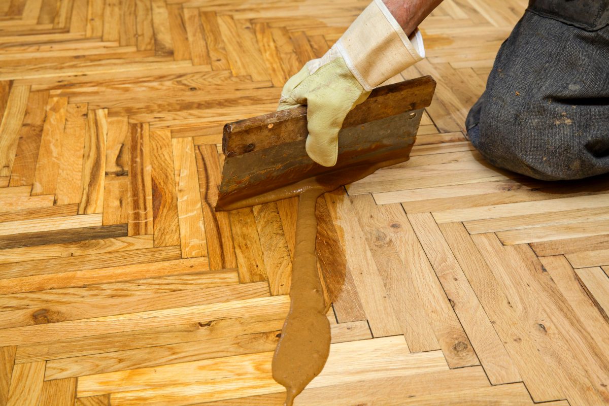 Varnishing of oak parquet floor, workers hand and tool